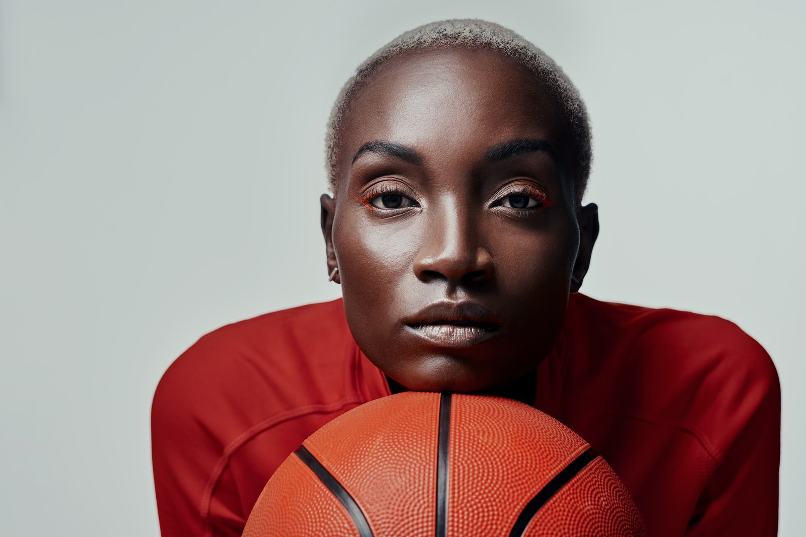 Studio shot of an attractive young woman playing basketball against a grey background